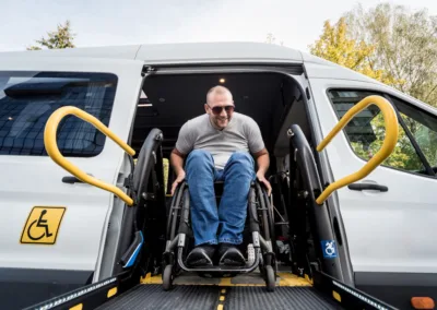 man in a wheelchair on a lift of a vehicle for people with disabilities