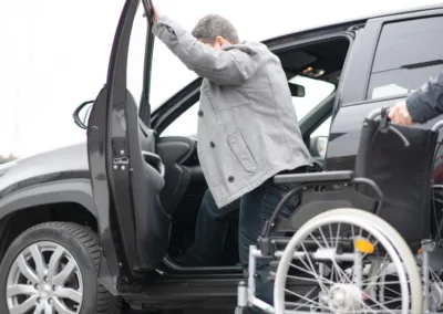 Disabled women getting out of taxi into wheelchair